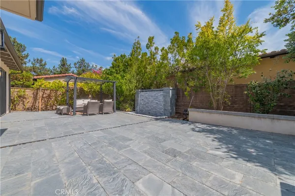 a backyard of a house with plants and trees with wooden fence
