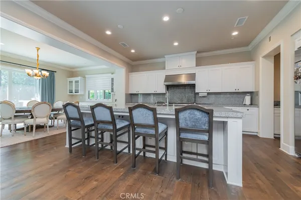 a large dining hall with stainless steel appliances granite countertop a stove a sink a dining table and chairs with wooden floor