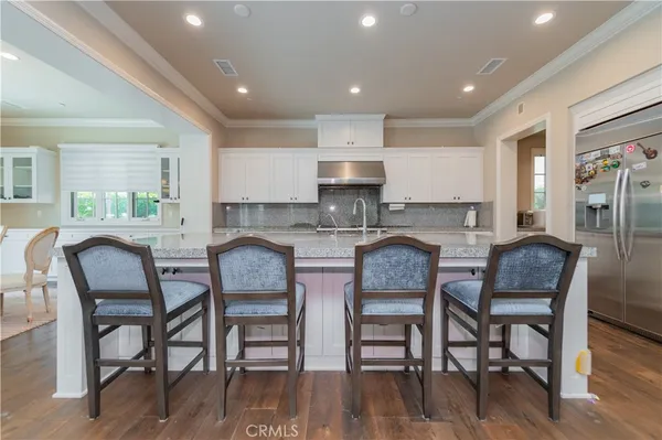 a kitchen with stainless steel appliances granite countertop a table chairs stove a sink dishwasher and cabinets with wooden floor