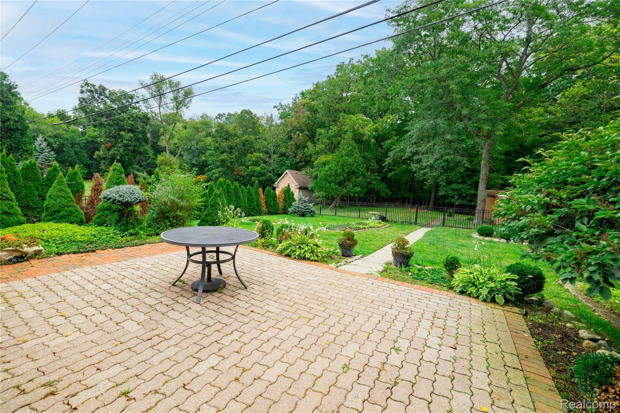 25645 Meridian Road Grosse Ile, MI 48138 - Photo 39 of 46 Paver patio with a brick border, expansive lawn, mature trees, manicured hedges, and a visible shed