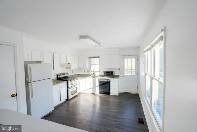 a kitchen with a refrigerator a stove top oven and white walls