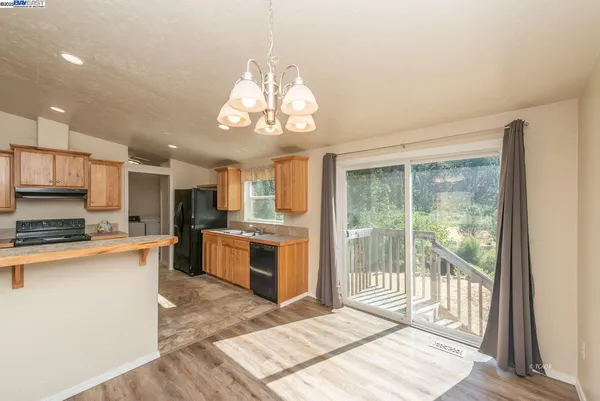 a large kitchen with stainless steel appliances granite countertop a stove top oven a sink dishwasher a dining table and chairs with wooden floor