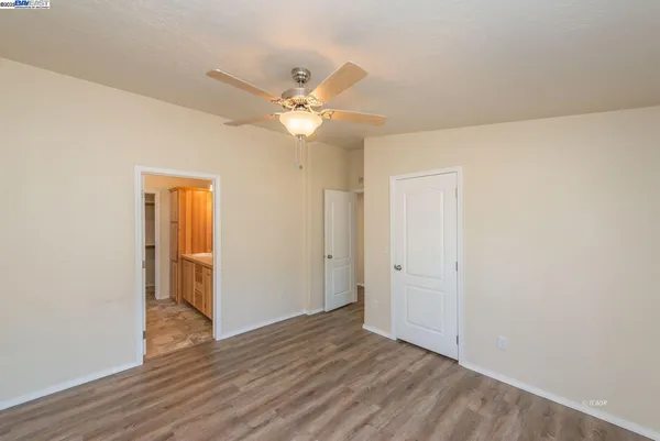 an empty room with wooden floor and a ceiling fan