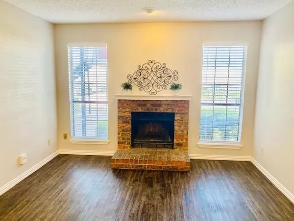 an empty room with wooden floor fireplace and windows