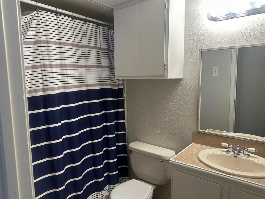 7621 McCallum Boulevard, Unit 108 Dallas, TX 75252 - Photo 18 of 26 a bathroom with a sink a toilet a mirror and a shower