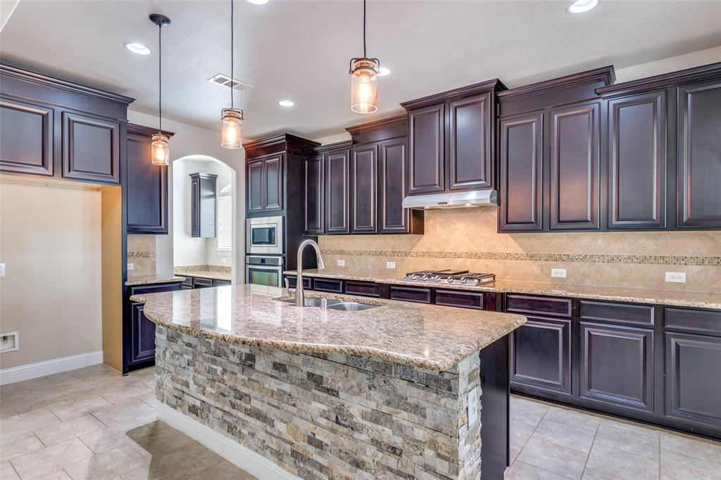 1505 5th Street Argyle, TX 76226 - Photo 11 of 25 a kitchen with stainless steel appliances granite countertop wooden cabinets a refrigerator and a sink