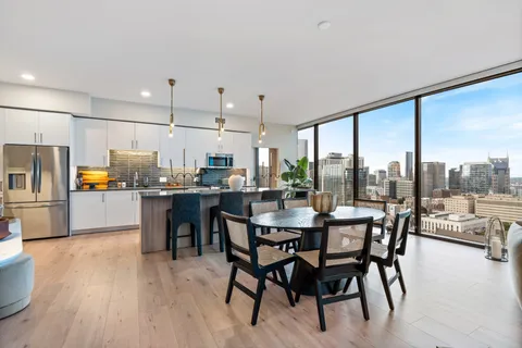 a view of a dining room and livingroom with furniture wooden floor a chandelier