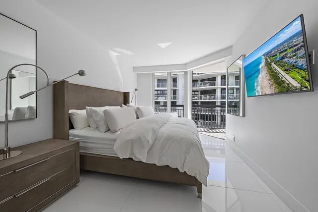 a bedroom with a bed a dresser and a large window