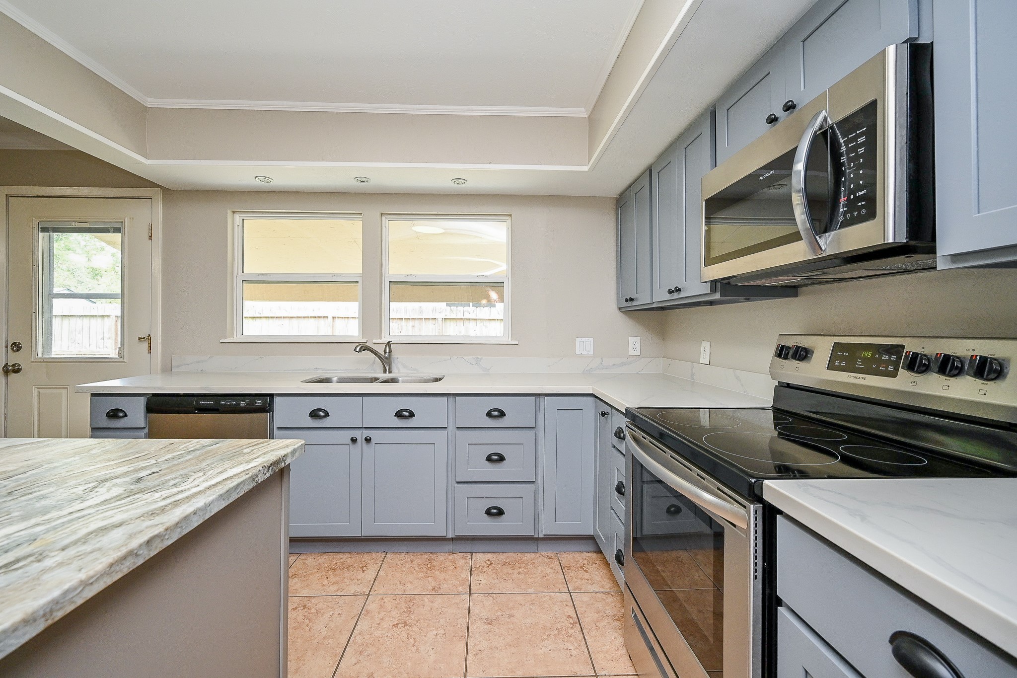 Updated kitchen with quartz countertops, stainless steel appliances, and shaker-style cabinetry in a modern gray finish.