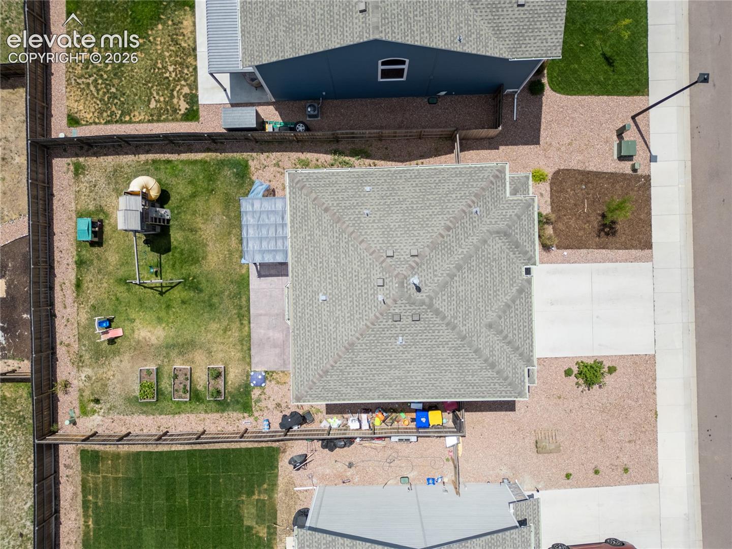 10993 Avena Road Peyton, CO 80831 - Photo 29 of 42 Property featuring a shingle roof, concrete driveway, and a fenced backyard with a lawn and raised garden beds