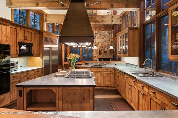 a kitchen with stainless steel appliances granite countertop a sink a stove and a wooden cabinets