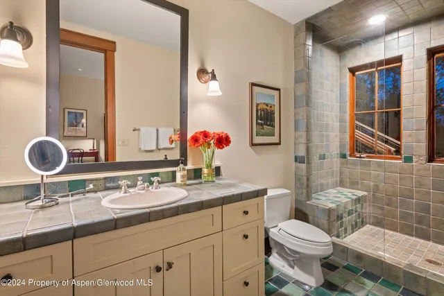 a bathroom with a granite countertop toilet sink and mirror