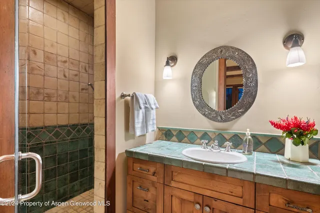 a bathroom with a granite countertop sink a mirror and shower