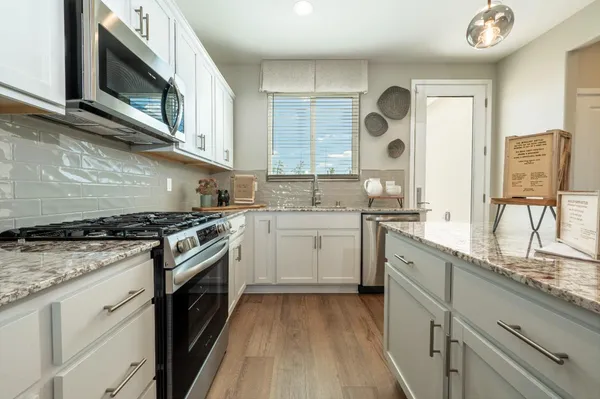 a kitchen with stainless steel appliances granite countertop a stove a sink and a microwave