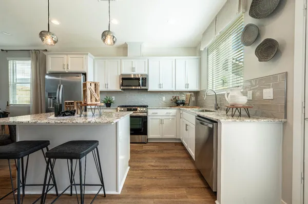 a kitchen with kitchen island granite countertop a sink a counter top space stainless steel appliances and cabinets