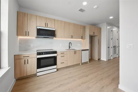 a kitchen with stainless steel appliances granite countertop a sink a stove a refrigerator and white cabinets
