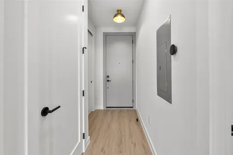 a view of a hallway with wooden floor and a bathroom