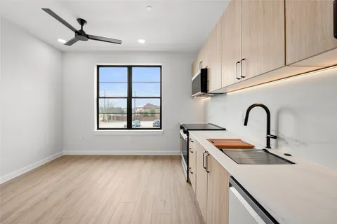 a view of a kitchen with a sink and dishwasher with wooden floor