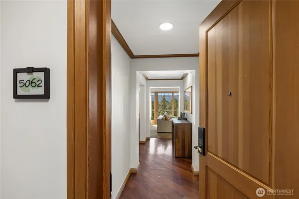 a view of a hallway with wooden floor and a livingroom with furniture