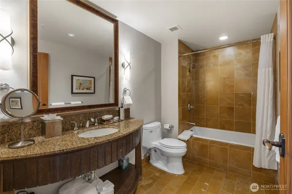 a bedroom with a bed wooden floor and couch