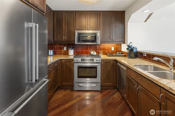 a kitchen with granite countertop a sink stove and microwave