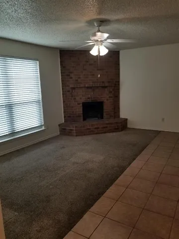 an empty room with fireplace chandelier fan and windows