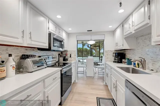 a kitchen with white cabinets sink and stainless steel appliances