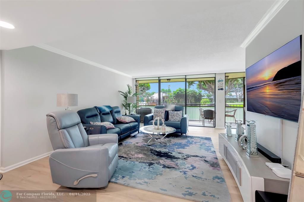 899 Jeffery Street, Unit 109 Boca Raton, FL 33487 - Photo 6 of 37 a living room with furniture a flat screen tv and a floor to ceiling window