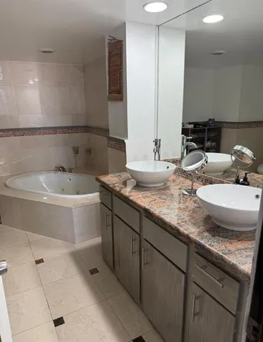 a bathroom with a granite countertop bathtub sink and mirror