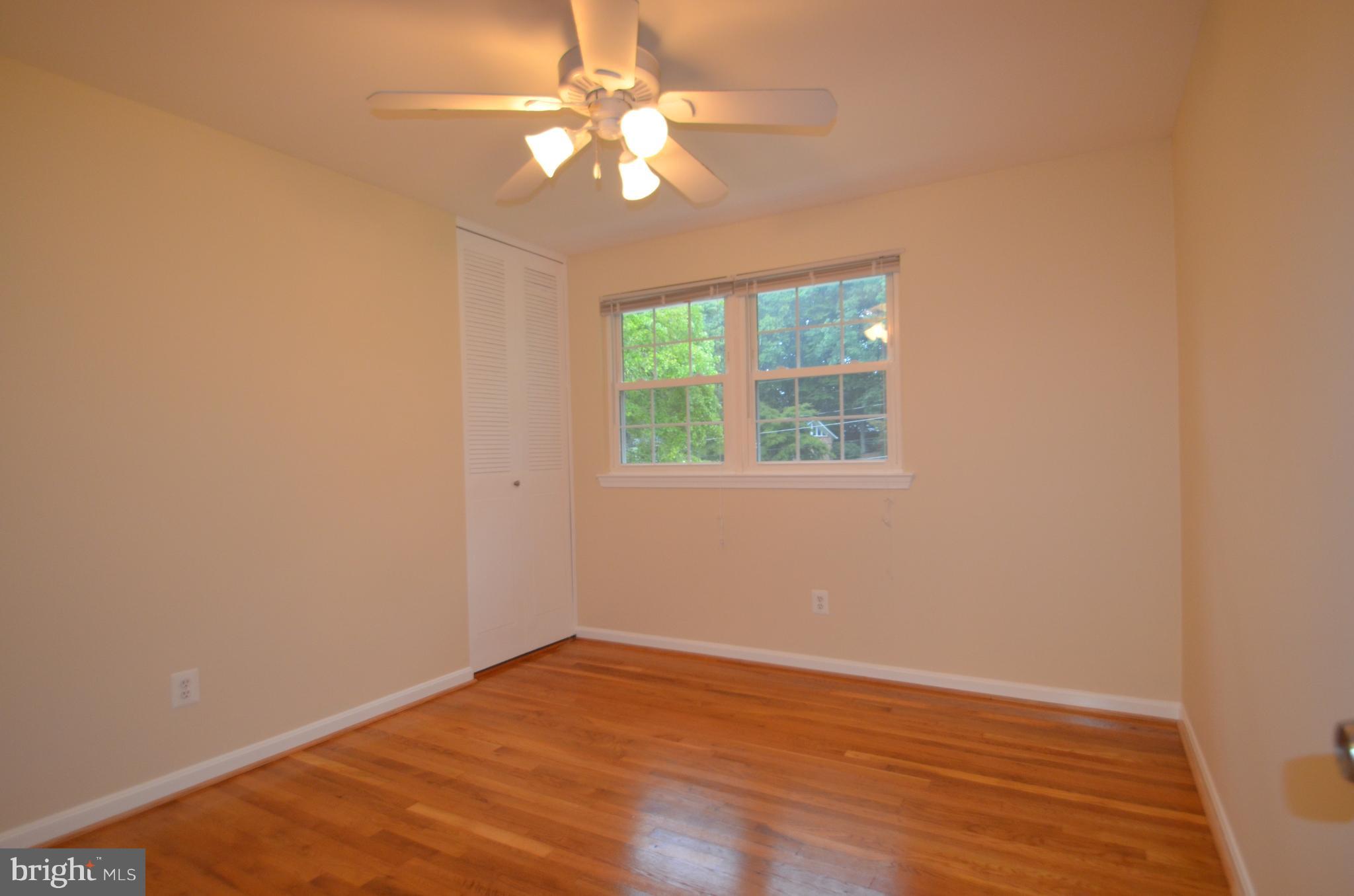 8627 Victoria Road Springfield, VA 22151 - Photo 18 of 30 an empty room with wooden floor fan and windows