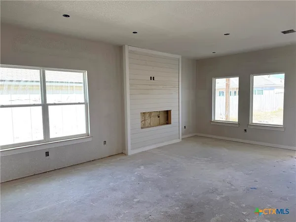 a view of an empty room with a window and fireplace