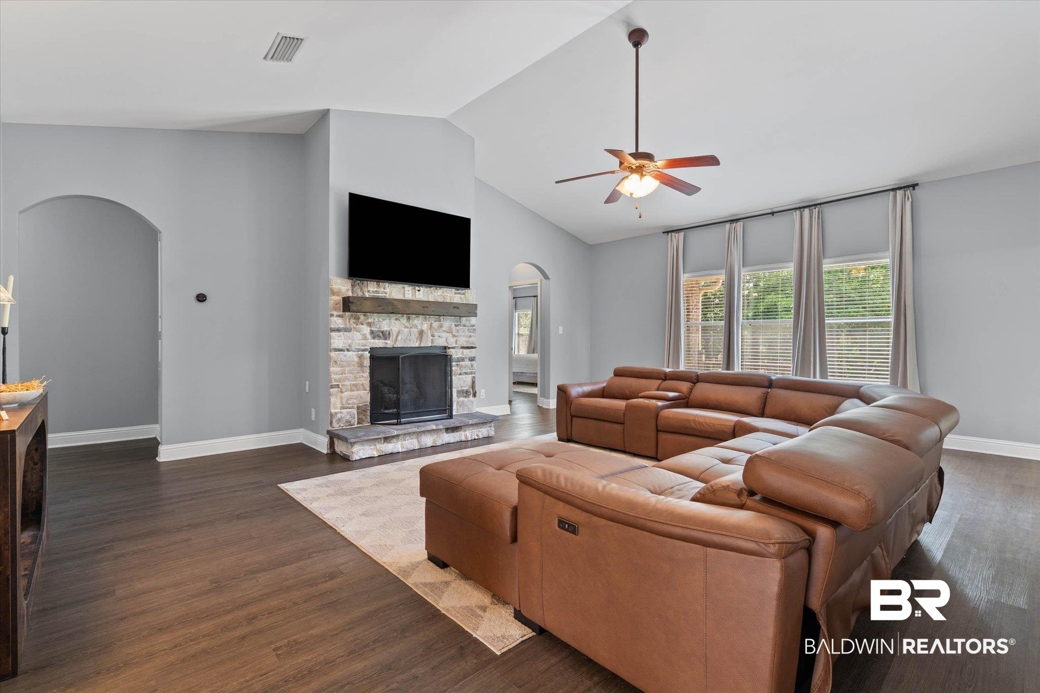 3739 Whitestone Drive Semmes, AL 36575 - Photo 3 of 25 Living area featuring a stone fireplace with a wood mantle, vaulted ceilings, wood-finish flooring, and multiple windows