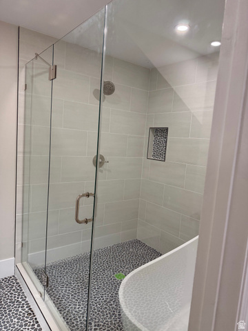 8965 Quail Run Drive Sandy, UT 84093 - Photo 49 of 56 Walk-in shower with clear glass enclosure, light grey subway tile walls, a built-in shower niche with mosaic tile, and a pebble-finish floor