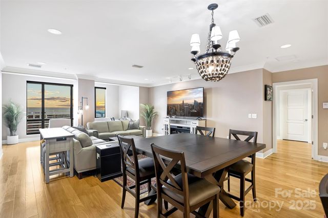 a view of a dining room and livingroom with furniture wooden floor a chandelier