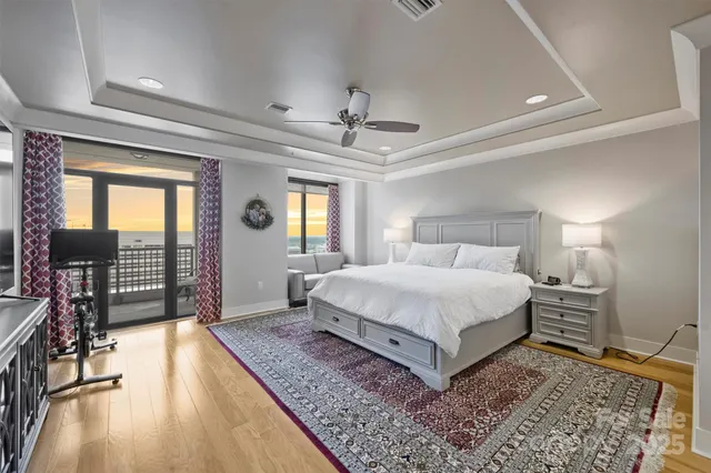 a spacious bedroom with a large bed a chandelier and windows