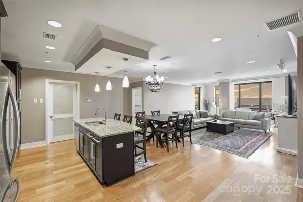 a large dining hall with stainless steel appliances granite countertop a stove oven a dining table and chairs with wooden floor