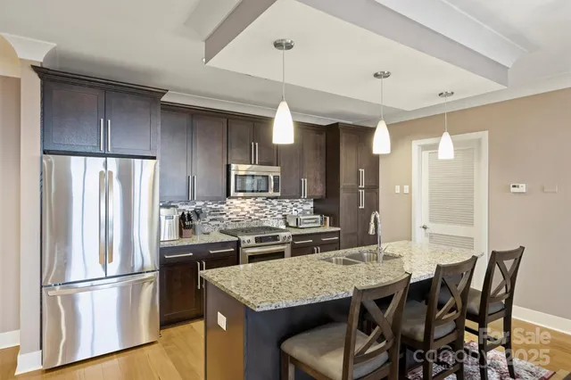 a kitchen with stainless steel appliances granite countertop a kitchen island a table and chairs
