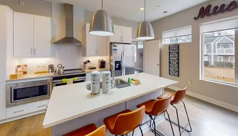 a kitchen with stainless steel appliances a sink a stove a table and chairs