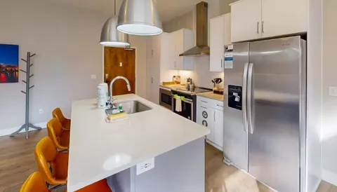 a kitchen with stainless steel appliances granite countertop a refrigerator a stove and a sink with wooden floor