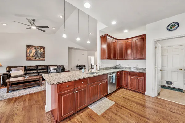 a kitchen with stainless steel appliances granite countertop a refrigerator a stove top oven and a dining table with wooden floor