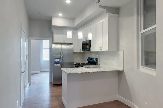 a kitchen with kitchen island granite countertop a sink cabinets and stainless steel appliances