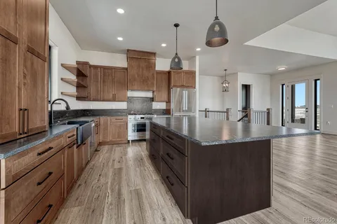 a kitchen with stainless steel appliances granite countertop a stove a sink dishwasher a refrigerator and a oven with wooden floor