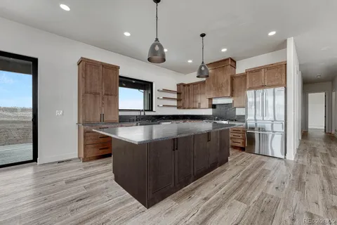 a large kitchen with stainless steel appliances granite countertop a large stove a sink dishwasher and a large refrigerator with wooden floor