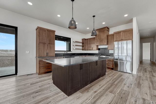 a large kitchen with stainless steel appliances granite countertop a large stove a sink dishwasher and a large refrigerator with wooden floor