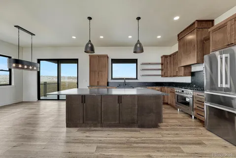 a large kitchen with stainless steel appliances kitchen island granite countertop a large counter top a stove a sink and a refrigerator