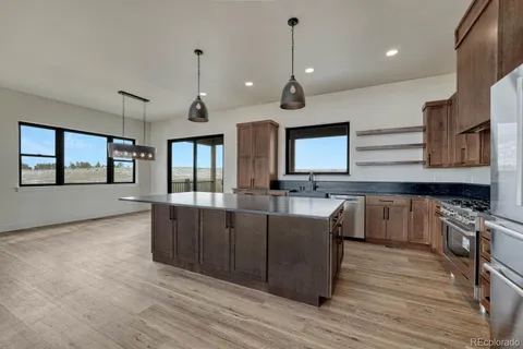 a kitchen with stainless steel appliances granite countertop wooden floors and view of living room