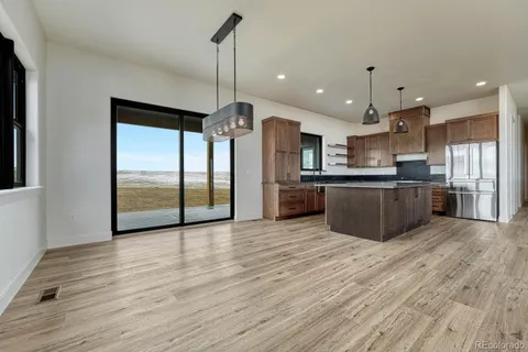 a large kitchen with stainless steel appliances kitchen island a large counter top and wooden floors