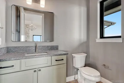 a bathroom with a granite countertop toilet sink and mirror