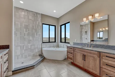 a bathroom with a granite countertop sink a mirror a bathtub and shower
