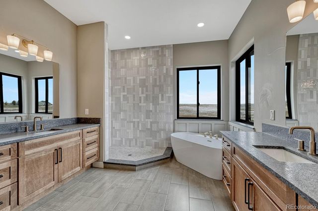 a bathroom with a granite countertop double vanity sink a mirror and a bathtub